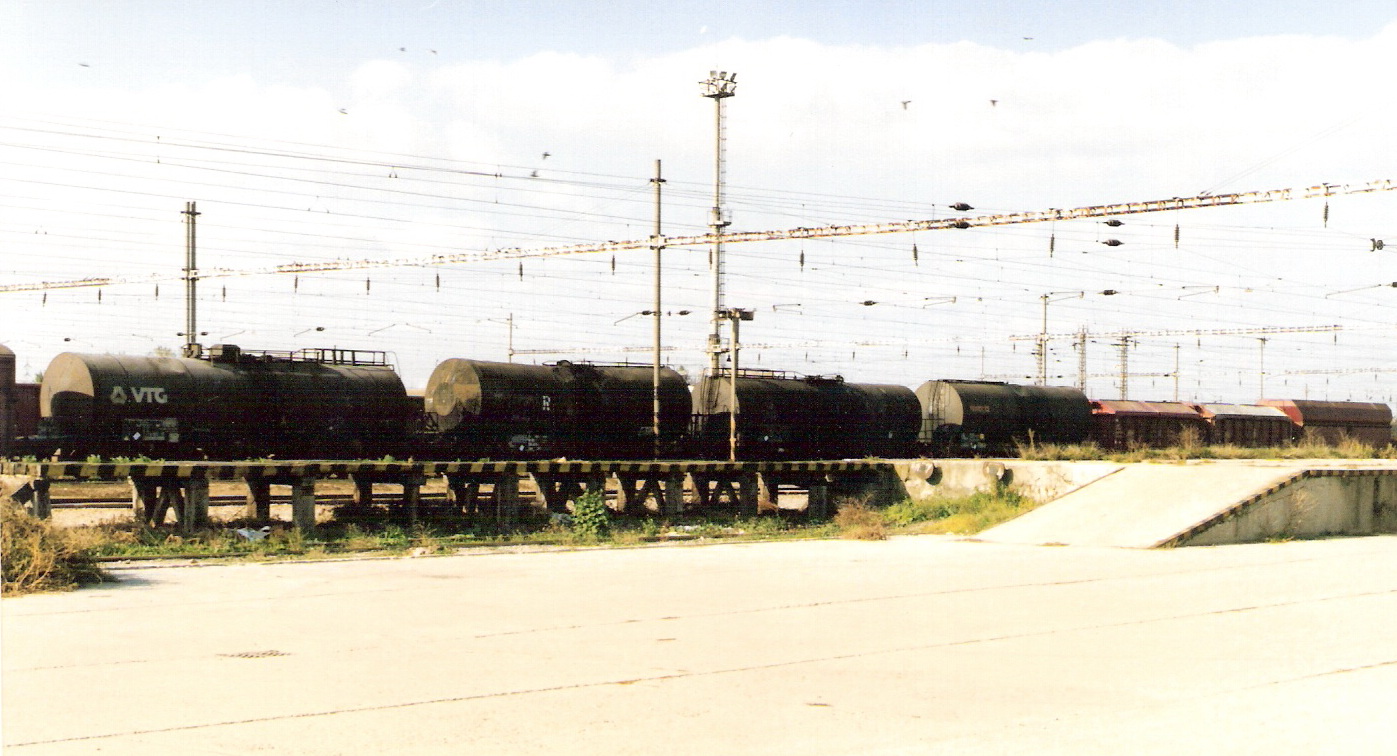  Leopoldov - nákladisko s drevenou nakladacou rampou. Vzadu cisterny, troleje, osvetľ. maják. Foto: M. Entner, 18.10.1994. 178 x 125, COLOR 