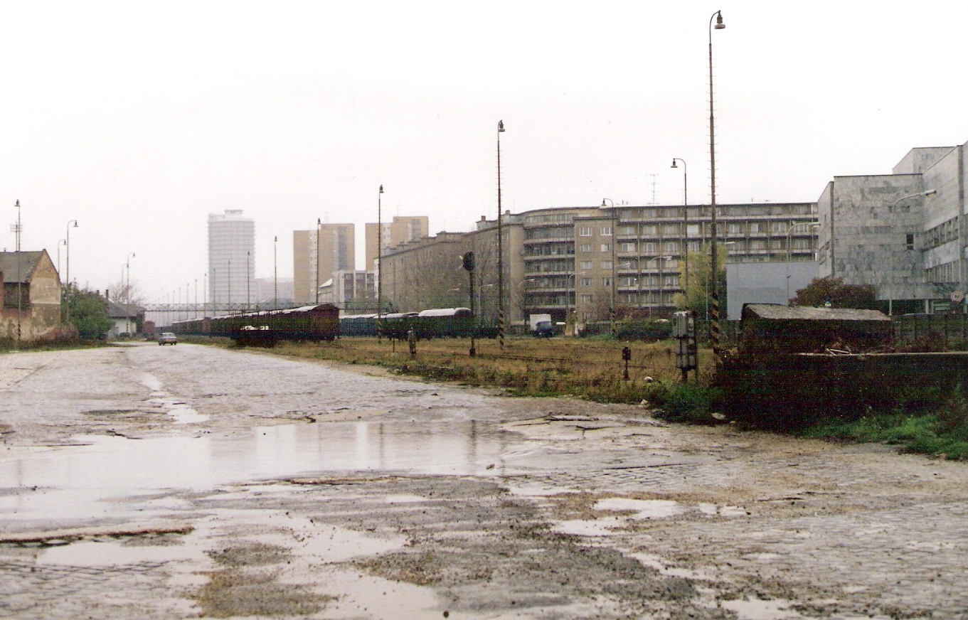  Bratislava filiálka - pohľad z nákladiska pri Šancovej ul. smerom do stanice. Výpr. bud., lávka, odstavené nákl. vozne, osvetľ, stožiare, vzadu výšk. voj. ubytovňa. Foto: M. Entner, 10.1995. 177 x 125, COLOR. 