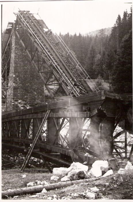  Trať Tisovec - Zbojská. Trosky mosta - kamen. pilier so šikmo opretými priamopás. poľami s normálnerozchod. koľajou a ozubnicou. Vpredu polož. ďalšie oblúk. pole. Text: Tisovec. Foto: ČSD, cca 1945. 116 x 175 
