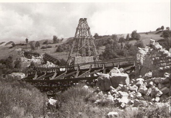  Hanušovce - trosky železnič. mosta v pahorkovitej krajine - lichobežn. most. polia v na zemi, rozváľané kamen. piliere, jeden v stavbe s lešením. Text: Hanušovce - zničený most. Foto: ČSD, cca 1945. 171 x 115 