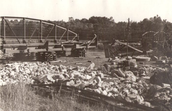  Trať Hodonín - Holíč. Trosky poloparabolic. mosta v km 3,009, zdvih. konštruk. obidvoch krajných polí, strhnutá konštruk. stred. poľa. Vpredu stav. kameň, telegraf. tyč. Vzadu rieka a les. Anon., cca 1945 225 x 150. 
