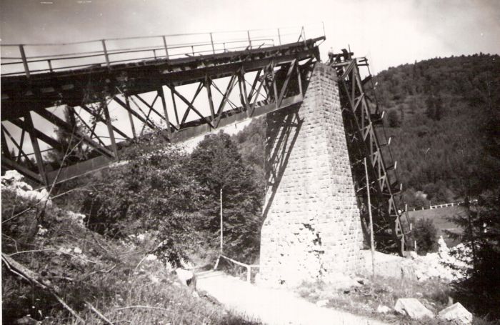  Trať Tisovec - Zbojská. Trosky mosta - kamen. pilier so šikmo opretými priamopás. poľami. Cesta pri pilieri i na protiľahlom úbočí. Hory. Text: Tisovec. Foto: ČSD, cca 1945. 115 x 172 