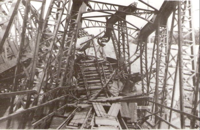 Trenčín. Zničený elipt. železn. most cez Váh. Pohľad v osi koľaje do zničenej konštrukcie. Text: Oblúk zničeného žel. mosta. Anon., cca 1945. 130 x 90, Repro : J. Fojtík 