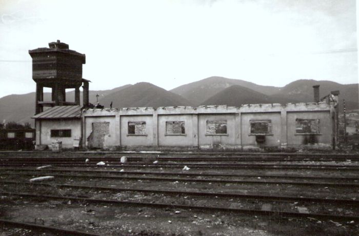  Vrútky. Pohľad od kraľovanského konca výprav. budovy nákl. stanice k vodárni depa. Vodáreň, koľaje pri točni, dielenská budova bez strechy, vzadu hory. Anon., cca 1945. 171 x 117 
