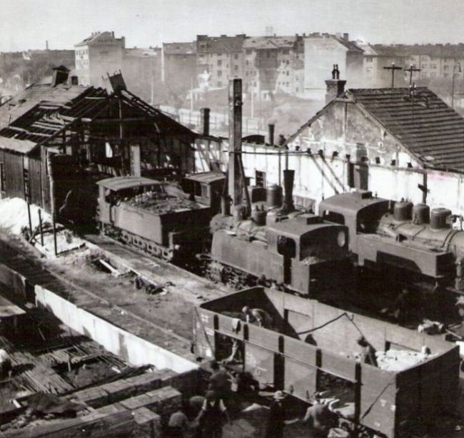  Bratislava Nivy - rozvaliny depa s 275 MÁV, 313.6, 331.0. Vpredu uhliak SŽ. Vzadu M 130.3 (?), posun. 313.6 a Karadžičova ul. s rozbitými domami. Text: Výhr. v Brat. N. Meste po bombard. Foto: Kľučka, 1945. 124 x 127 