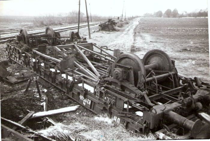  Prevrátený nízkostenný vozeň DR, vzadu zhlavie výhybne na jednokoľaj. trati. Telegraf. tyče, pole. Text: Krpeľany. Foto: Morávka, cca 1945. 180 x 124 