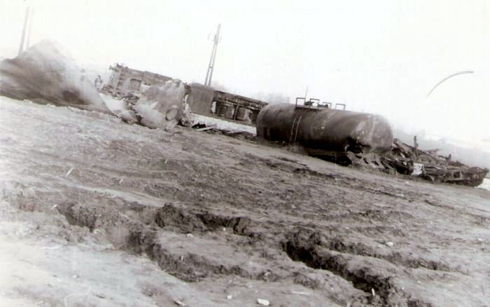  Neh. na spojke medzi ÚNS a Slovnaftom 6.2.1974. Vľ. plášť cist. po explózii, časť nízkost. vozňa, vpr. kotol cist., vedľa podvozky. Za traťou prevr. T 669.0. Text: Trosky po žel.zráž. pri Slovnafte. Anon., 115x80 