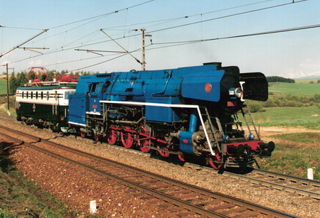  Elektrický rušeň E 499.0047 + parný rušeň 477.013 na trati Poprad - Štrba. Vzadu lúky a zasnežené Tatry. Foto: P. Kukučík, 29.4.2000. 174 x 126, COLOR. 