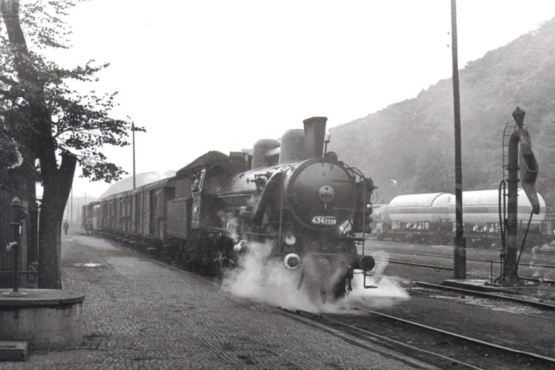  Parný rušeň 434.2338 v žst. Kralupy pri posune so súpravou D (pre nákl. vlaky). Pohľad zprava zpredu. Vpravo vodný žeriav, cisterny na P-B, vľavo dláždená plocha. Anon., 28.9.1972. 175 x 126 