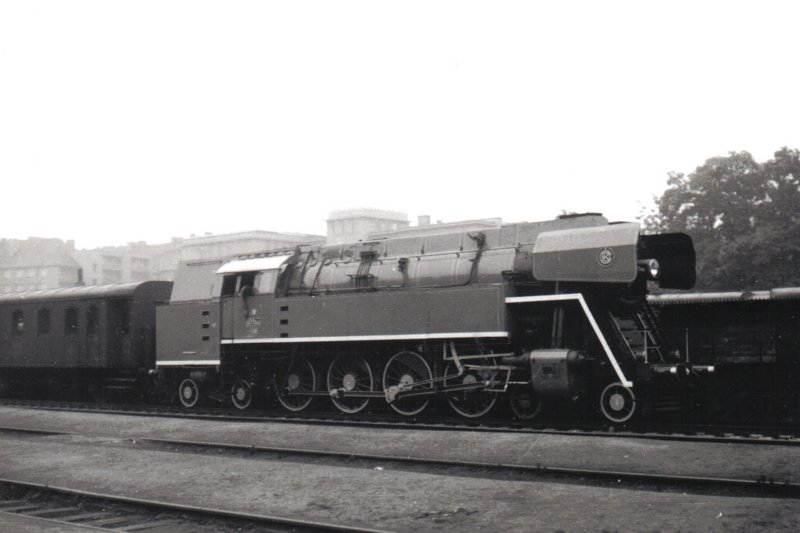  Parný rušeň 477.043 + Ce v žst. Praha Dejvice počas prvej jazdy po oprave v ŽOS Č. Velenice. Pohľad zprava zpredu. Vzadu obytné budovy. Foto: J. Máša, 21.9.1980. 180 x 130 