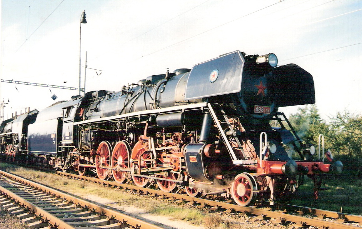  Parný rušeň 498.104 v žst. Rusovce (?), za ním 475.196. Pohľad zprava zpredu. Trolej, osvetľ. stožiar. Foto: M. Entner, cca 2000. 148 x 100 