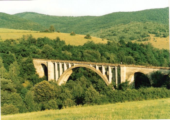  Betónový oblúkový most s dvoma postrannými oblúkmi v hornatej krajine. Text: Most pri Magnezitoviach na trati Slavošovce - Revúca. Foto: P. Kallo, cca 1995. 176 x 125, COLOR 