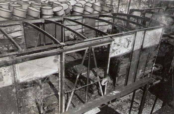  Bratislava sriaď. nádražie. Rozbitý a zhorený krytý nákl. vozeň v smerovej skupine po bombardovaní. Vzadu volne ložené sudy. Anon., 1945. 123 x 80 