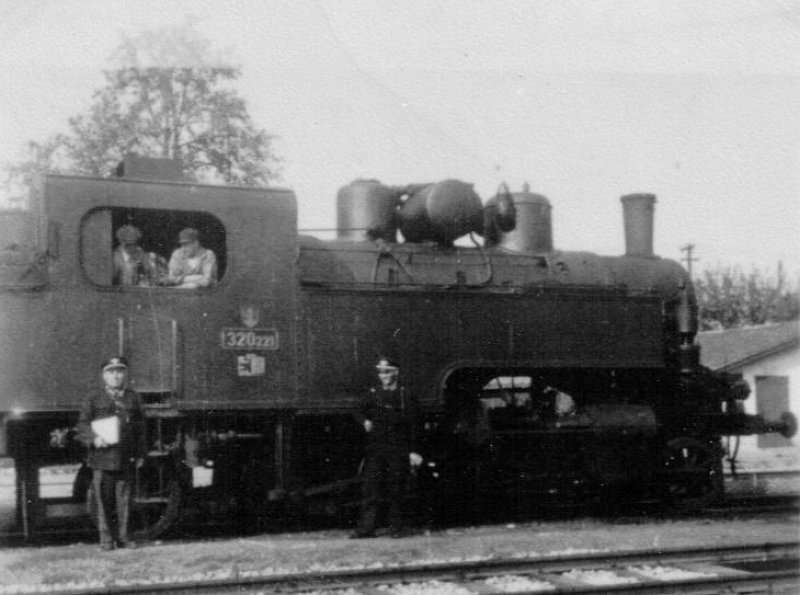  Parný rušeň 320.221 SŽ v žst. Malacky. Pohľad zprava. Pózujúca rušňová čata a ďalší dva železničiari v rovnošatách. Anon., 1942. 62 x 62. Repro. M. Entner 
