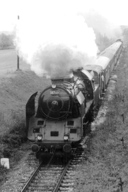  Parný rušeň 387.043 so súpravou Bai a parným postrkom v plytkom záreze na jednokoľajnej neelektrifikovanej trati s nadzem. telef. vedením. Foto: M. Fogl, cca 1980. 105 x 148 