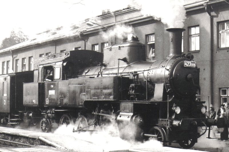  Parný rušeň 423.009 + vozeň Ci s plochou strechou v žst. Svitavy, pohľad zprava zpredu. Vzadu priečelie budovy. Foto: E. Hromadník, cca 1990. 170 x 120 