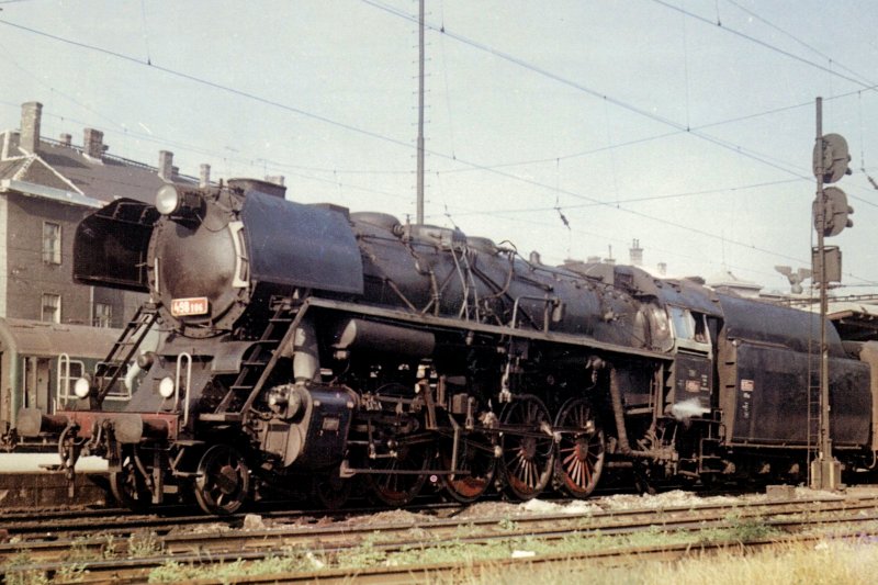  Parný rušeň 498.106 pri 2. peróne žst. Bratislava hl. st. smerom na Raču. Vpravo odchod náv. ZSSR, vzadu časť výpravnej budovy. Pohľad zľava zpredu. Foto: A. Molnár, 8.1967. 165 x 118, COLOR 