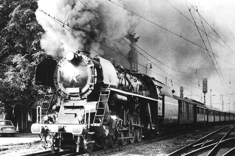  Parný rušeň 498.106 + F (rybák) + salón. vozeň + súpr. rybákov odchádza zo žst. Považská Bystrica do Žiliny. Pohľad zľava zpredu. Trolej, odch. náv. AŽD. Anon., 29.9.1983. 122 x 83 