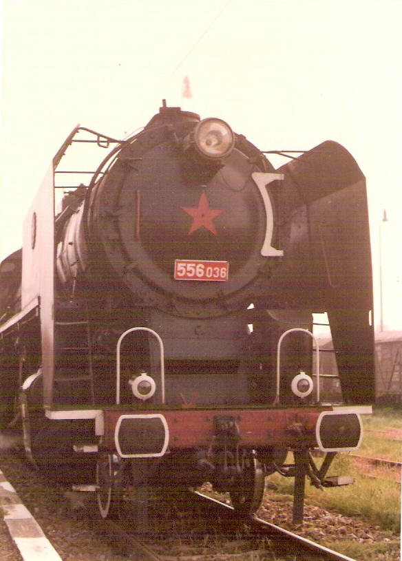  Parný rušeň 556.036 pri nástupišti žst. Bratislava-Petržalka. Pohľad zpredu. Trolej, osvetľ. stožiare. Foto: Z. Piešová, 6.1989. 74 x 103 