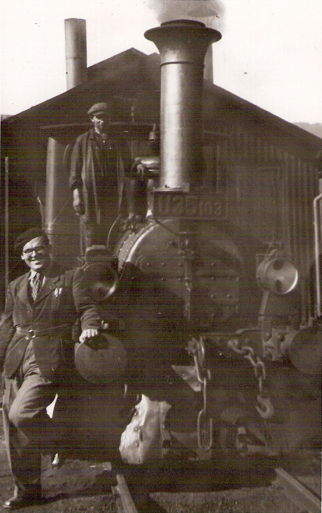  Úzkorozch. parný rušeň U 35.103 pred remízou v Banskej Štiavnici. Pohľad zpredu. Pri rušni vľavo Ing. Miroslav Héger, vzadu na ochoze rušňa robotník v pracovnom. Anon., 9.1949. 81 x 128 