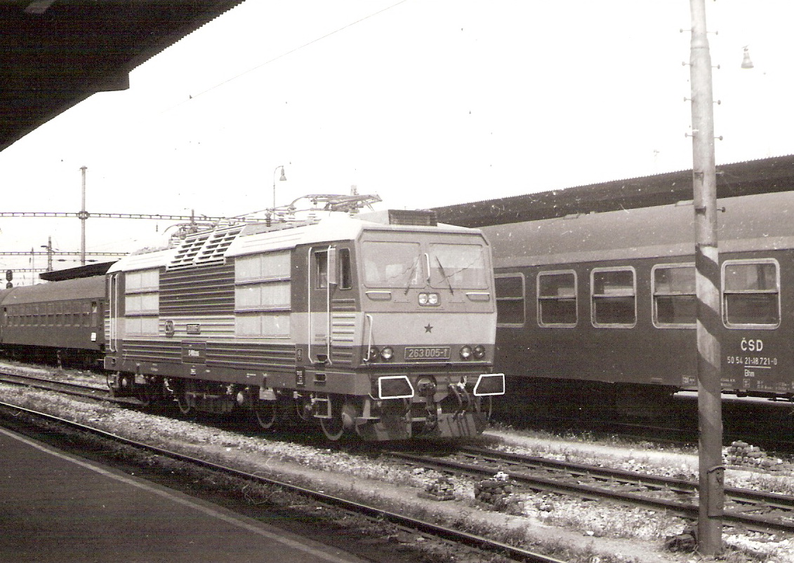  Elektrický rušeň 263 005-1 v žst. Bratislava Nové Mesto. Pohľad predobočný, z krytého perónu. Vzadu súprava vozňov Bai pri susednom krytom peróne. Foto: Z. Piešová, cca 1990. 147 x 106 