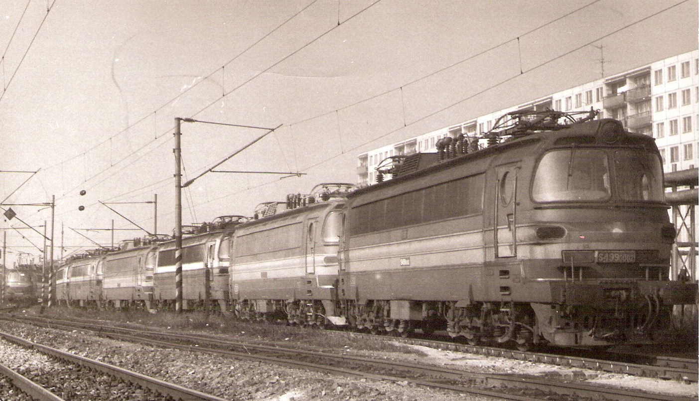  Elektrické rušne 240 002, 137, 114, 134, 074, 030 a 041 na prích. koľaji a pri St. 7. starého depa Bratislava východ. Pohľad predobočný. Vpravo vzadu panelák. Trolej. Foto: P. Pytel, 20.2.1990. 179 x 123. 