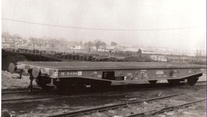  Nákladný štvornápravový plošinový vozeň Pa. Pohľad predobočný. Vzadu skládka podvalov, obec a hory. Foto: Anon., cca 1953. 240 x 178 