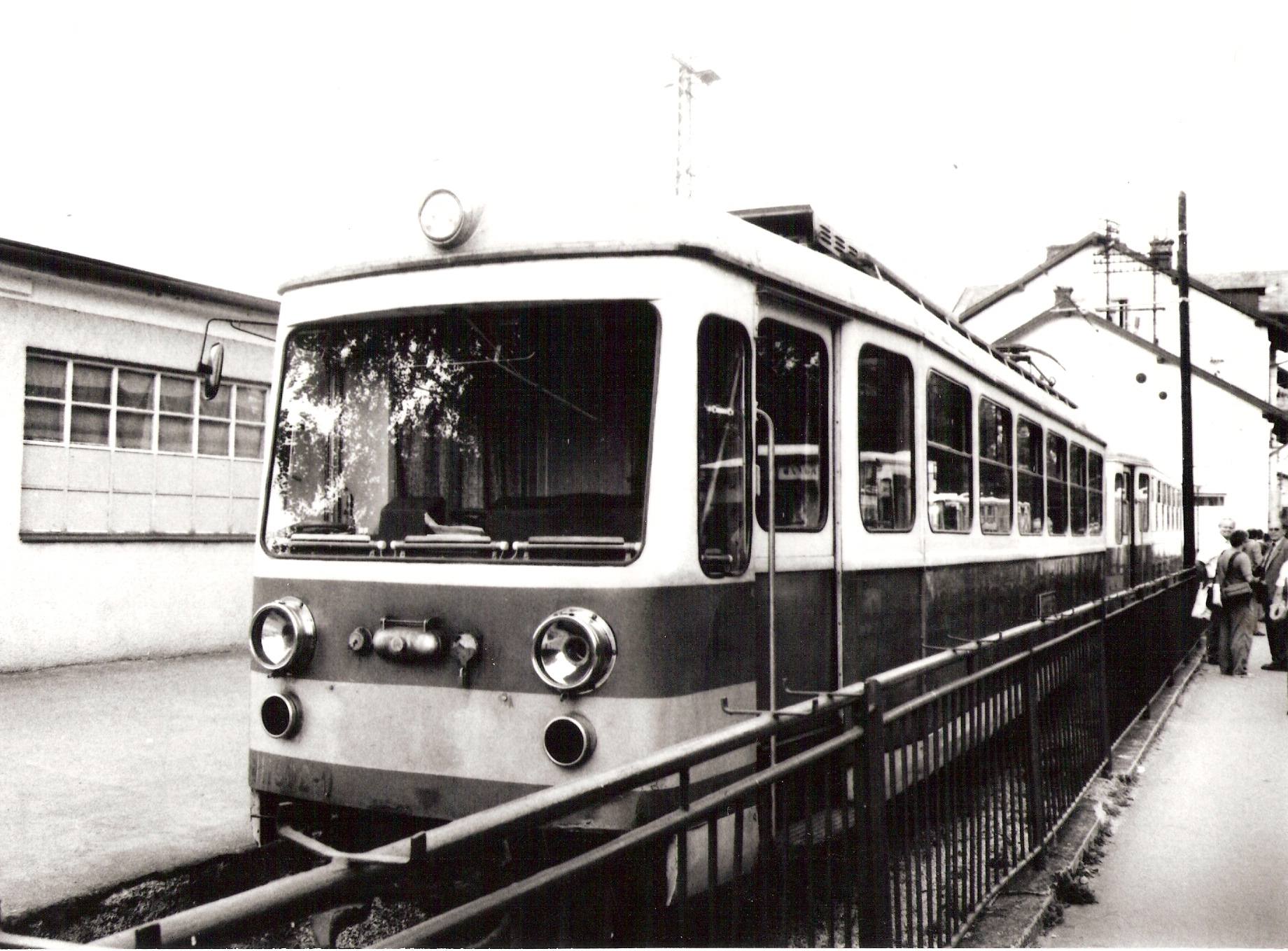  Elektrický motorový vozeň radu 411 9 v žst. Trenčianska Teplá. Pohľad predobočný. Vpravo vzadu výpravná budova, vľavo budova úzk. železnice. Vpravo stojí Ing. M. Doubek. Foto: A. Královič, cca 1990, 238 x 173 