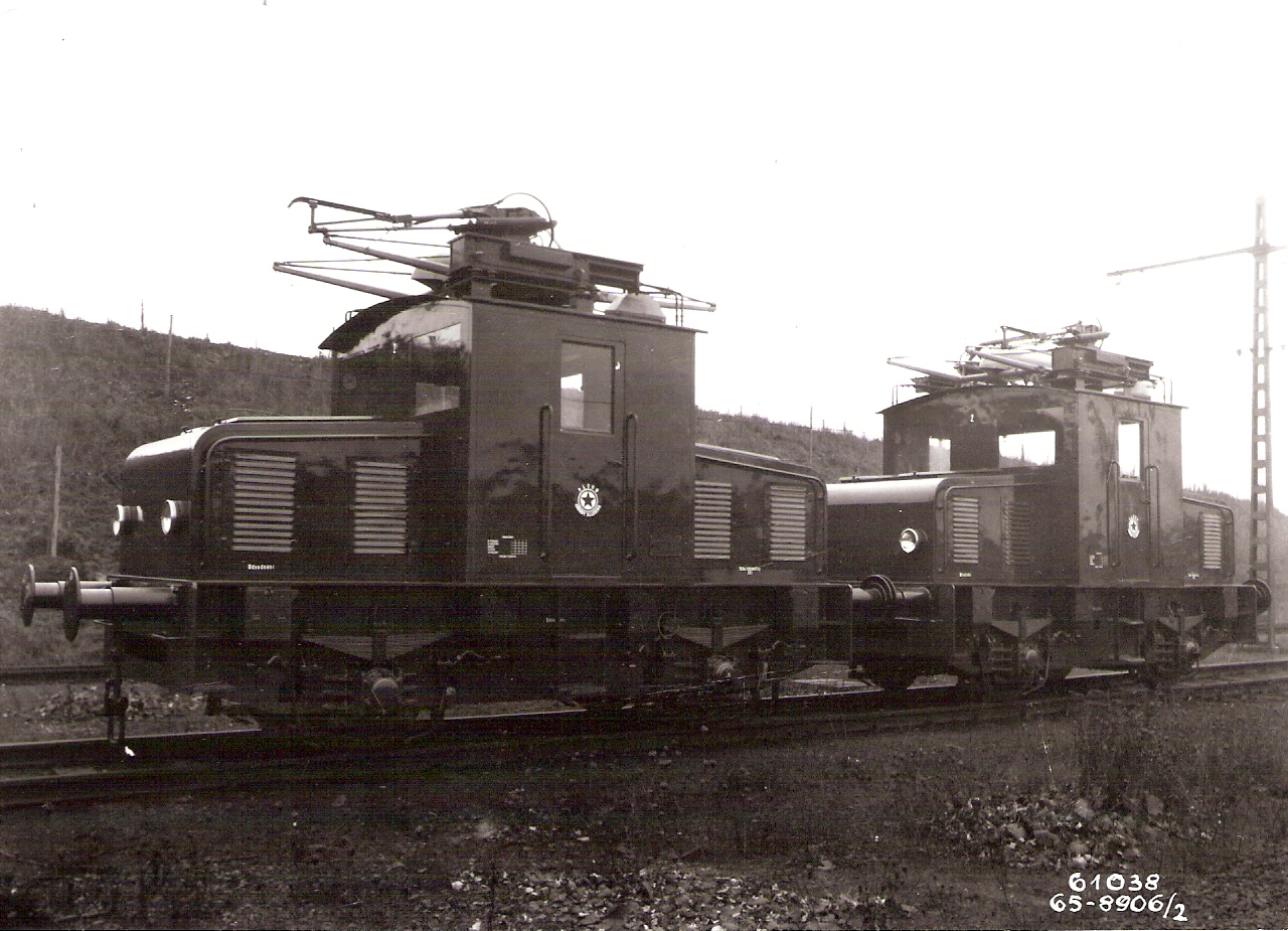  Dva elektrické dvojnápravové rušne s vežovým stanovišťom ZVIL pre priemysel po výrobe. Pohľad predobočný. Vpravo stožiar TV. Foto: Anon., cca 1955. 167 x 120 