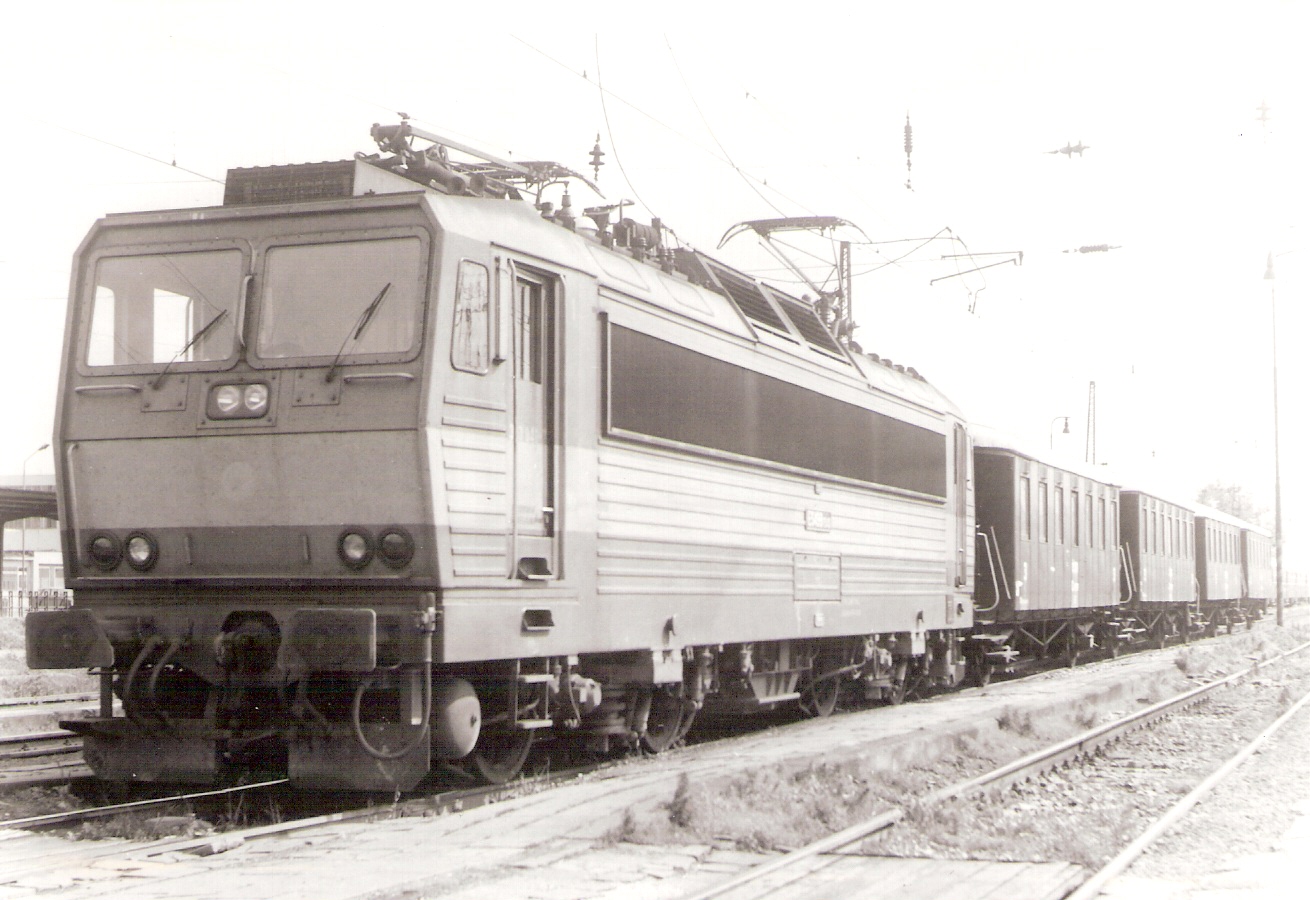  Elektrický rušeň ES 499.3 so 4 Ci vozňami MDC Bratislava v žst. Pohľad predobočný. Vpredu prechod medzi perónmi, vľavo vzadu časť krytého perónu. Osvetľ. stožiar, trolej. vedenie. Foto: O. Čížek, cca 1990. 167 x 120 