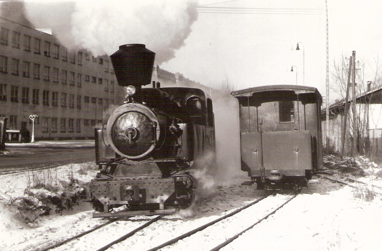  Úzkorozch. parný rušeń C 760/90d v Hronci. Zimný pohľad zľava zpredu. Vľavo vzadu adm. budova zlievarní, vpravo vozeň Ci/u a garáže LZ. Foto: D. Selecký, cca 1990. 175 x 120 