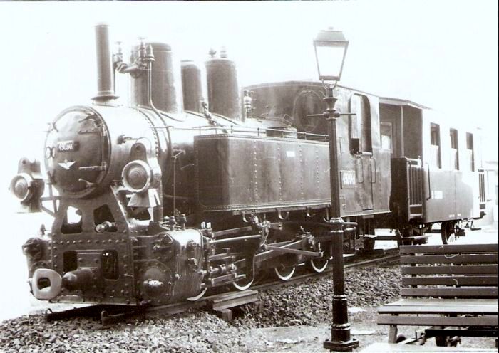  Úzkorozch. parný rušeň 490 041 MÁV s trojoknovým dvojnápr. vozňom v priestoroch riaditeľstva železníc Szombathely. Osvetľ. stĺp s petrolej. lampou. Pohľad zľava zpredu. Foto: Z. Piešová, 27.11.1986. 130 x 90 