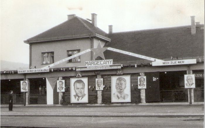  Margecany - výpravná budova. Čelný pohľad zo strany koľají na košická časť priečelia. Socialistická výzdoba. Foto: Anon., cca 1850. 165 x 120 