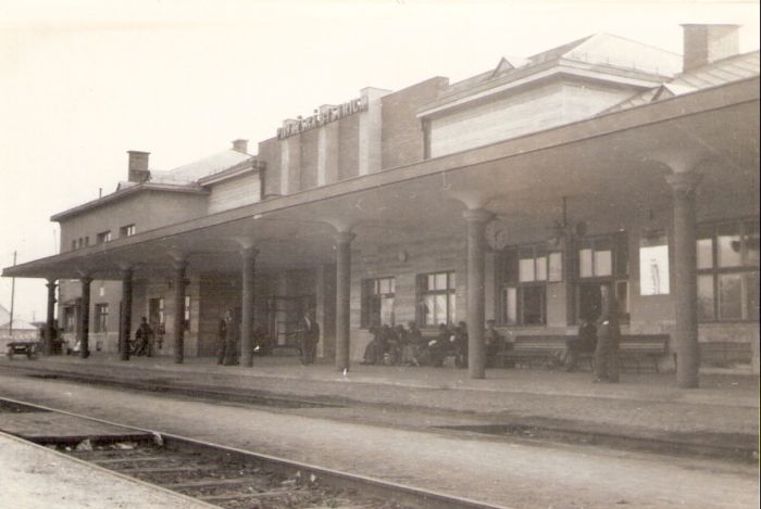  Považská Bystrica - výpravná budova nová. Šikmý pohľad zo strany koľají od Bratislavy na žilinskú časť budovy. El. hodiny pod strechou perónu, amplión. Foto: Anon., cca 1950. 132 x 86 