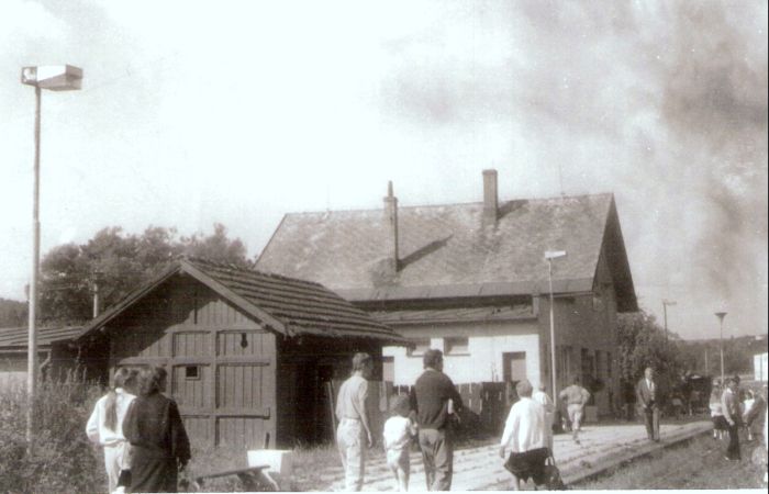  Staškov - výpravná budova. Šikmý pohľad zo strany koľají od Čadce. Vpredu sklad kombinovaný s WC. Ľudia. Foto: J. Kubáček. 14.8.1994. 180 x 122 