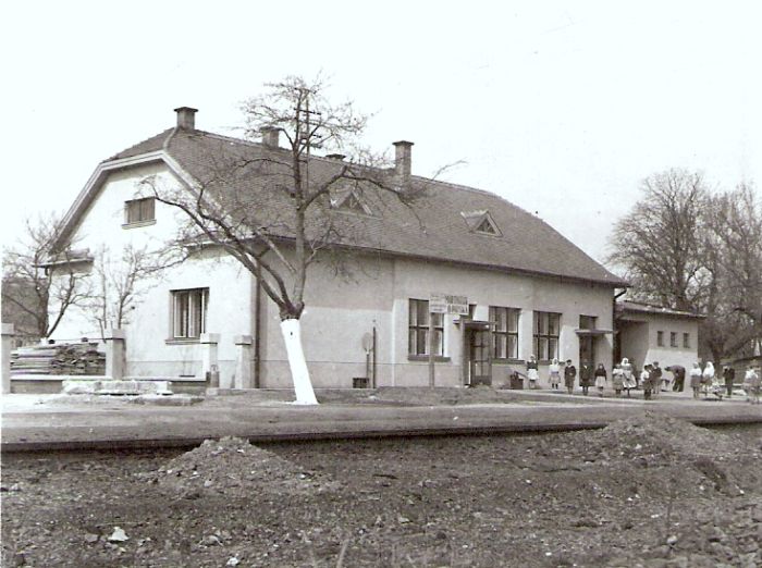  Trebišov - výpravná budova (provizórna počas výstavby ?). Šikmý pohľad zo strany koľají od Humenného. Ľudia v civile a krojoch. Foto: Anon., cca 1947. 93 x 92 