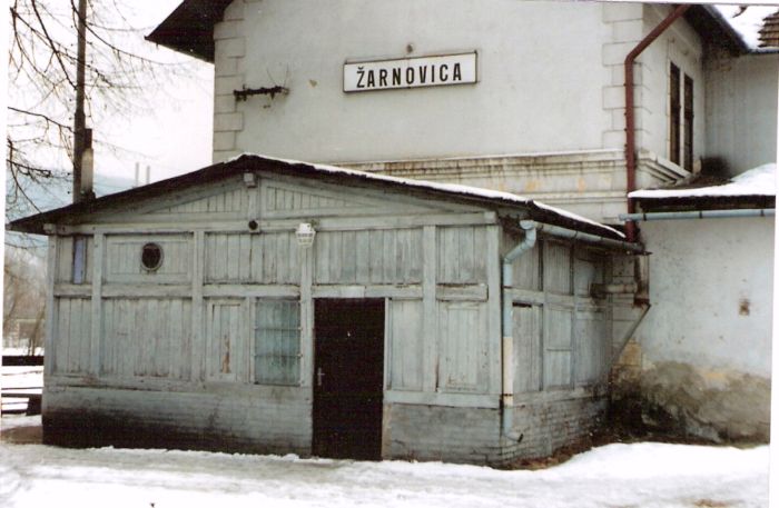  Žarnovica - výpravná budova. Zimný šikmý pohľad z predstaničného priestoru od Zvolena na drevenú verandu na zvolenskej strane budovy. Foto: Anon, 1996. 125 x 88, COLOR 