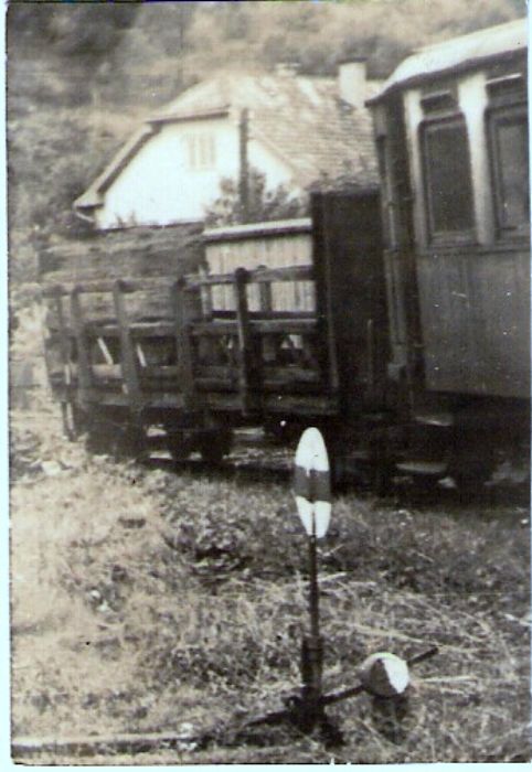  Vígľašská lesná železnica - zrejme stanica Vígľaš. Štvornápravový plošinový vozeň s rebrinovými bočnicami, vpravo koniec tramvaj. prívesu. Vpredu výhybka, vzadu obytný dom. Foto: V. Hlávek, cca 1975. 43 x 63 