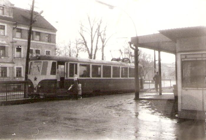  Trenčianska Teplá - el.st. Šikmý pohľad zo strany koľají normálneho rozchodu od Žiliny na nástupište. Pri ňom EMU 46.0. Vľavo vzadu budova kasárne, vpravo prístrešok nástupišťa. Foto: V. Hlávek, 1978. 90 x 62 