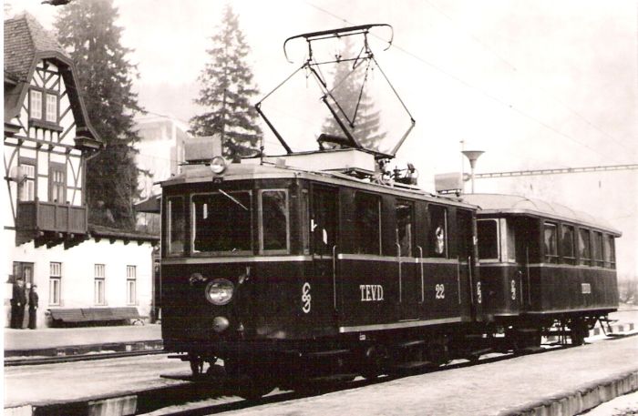  Hist. Elektr. motor. vozeň EMU 26.001 (TEVD 22) so zimným prívesným vozňom v stanici Starý Smokovec. Pohľad predobočný. Vľavo časť výpravnej budovy. Foto: D. Selecký, cca 1995. 130 x 89 