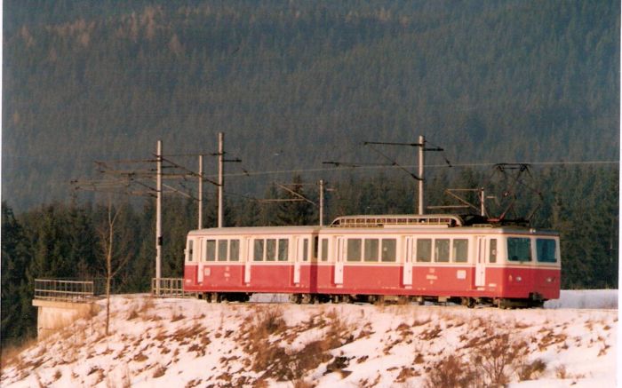  Elektrická motorová ozubnicová jednotka EMU 29.0002 na nízkom násype. Pohľad predobočný. Vľavo betónový most, vzadu zalesnená hora. Foto: Z. Piešová, 2.1992. 130 x 87, COLOR 