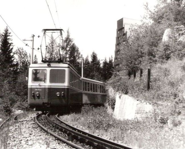  Elektrická motorová ozubnicová jednotka EMU 29.0002 pri výjazde zo stanice Štrbské Pleso. Pohľad zpredu. Vpravo hore hotel Panoráma. Foto: D. Fedin, 19.6.1988. 178 x 131 