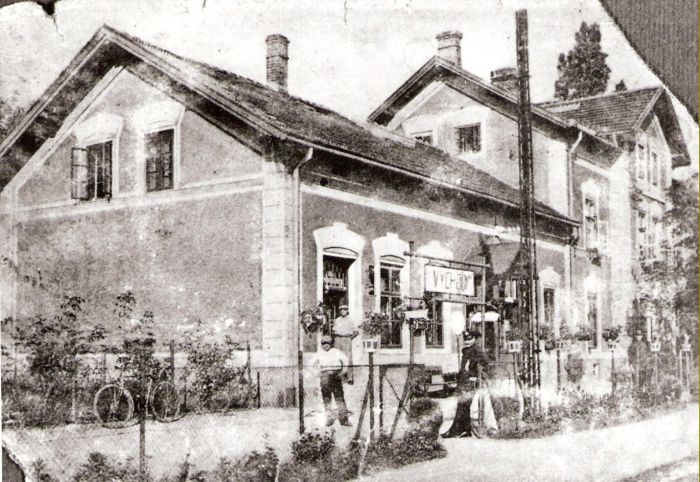  Bratislava sriaď. nádražie. Pohľad na výpravnú budovu od koľají. Vpredu plot s nápisom VÝCHOD, osvetľ. Kandeláber, dvaja civili a dvaja železničiari. Anon., cca 1930. 174 x 122 