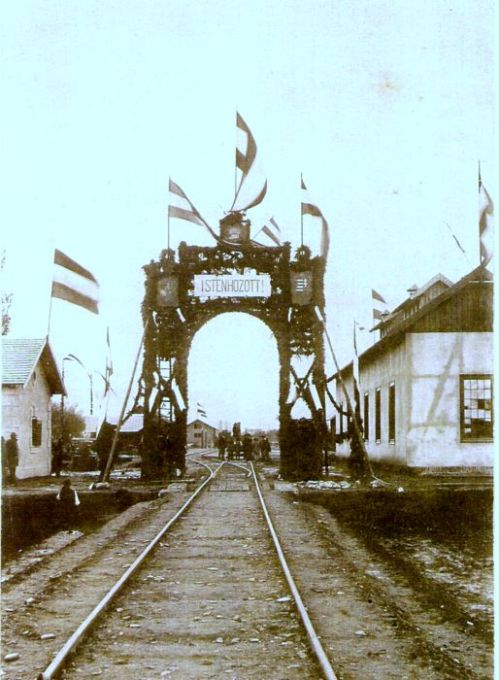  Spišské Podhradie - zhlavie na Spišské Vlachy. Pohľad v osi koľaje od Spišských Vlachov. Slavobrána pre prvý vlak, vpravo časť remízy, vľavo časť obytného domu. Foto: MUDr. Arthur Ernest Mueck, 14.10.1894, farebná xerokópia. 104 x 155 mm 