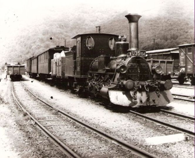  Úzkorozch. parný rušeň U 35.104 s 1 dvojnápr. vysokosten., 2 štvornápr. os. a 1 služ. vozňom v Hr. Dúbrave. Pohľ. zprava zpredu. Vľavo nákl. úzkorozch. vozeň a vodáreň, vpravo krytý vozeň SŽ norm. rozch. Foto: Anon., cca 1943. 200 x 167 