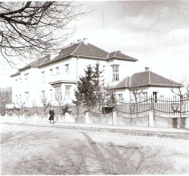 Košice - obytná budova v meste (železničná kasáreň). Nárožný pohľad. Kovaný plot, dláždená ulica. Foto: Anon., cca 1950. 97 x 89 