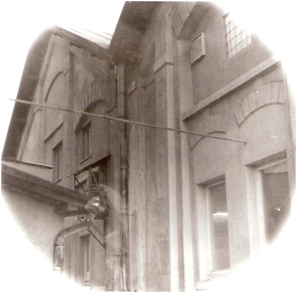  Žilina - depo, elektrická časť. Šikmý pohľad na fasádu bez brán zo strany predstaničného priestoru kolmo na staničné koľaje. Foto: J. Kubáček, 3.8.1994. 120 x 120 