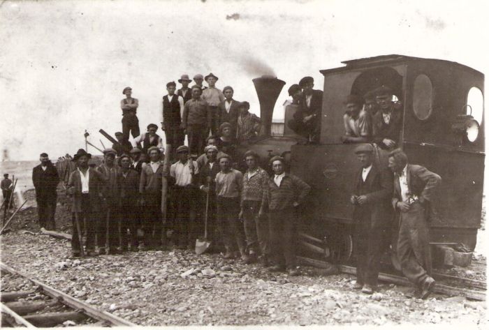  Parný rušeň úzkorozch. Orenstein a Koppel s dreven. huntíkmi so zeminou. Pohľ. zľava zozadu. Pred rušňom a na ňom ľudia v pracovnom a civile, niekt. s lopatami. Foto: Anon., cca 1930, zb. P. Faturu, Ladce, fotokópia. 144 x 95 