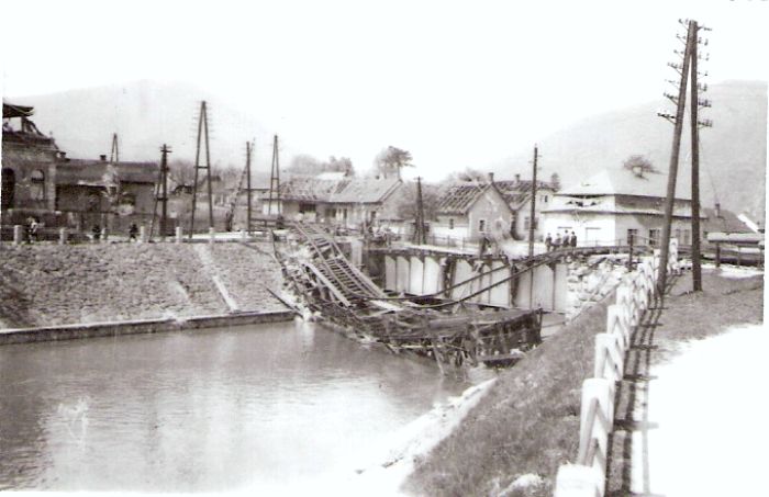  Vrútky os. st. - most pri žilinskom zhlaví. Šikmý pohľad od Martina. Vpredu zrútený most, vzadu plechový most v oprave. Priecestie s dvojdrôt. závorami. Rieka a nábrežie. Foto: Anon., 1945, zbierka Klabník. 86 x 56 
