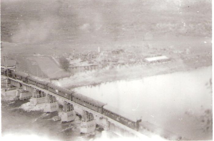  Strečno - most cez Váh. Os. vlak s 534.01 z podvozk. vozňov prechádza po drevenom most. provizóriu smerom do Žiliny. Pohľad zhora z ľavého brehu zo strany po prúde. Foto: Anon., 1945, zbierka Klabník. 84 x 56 